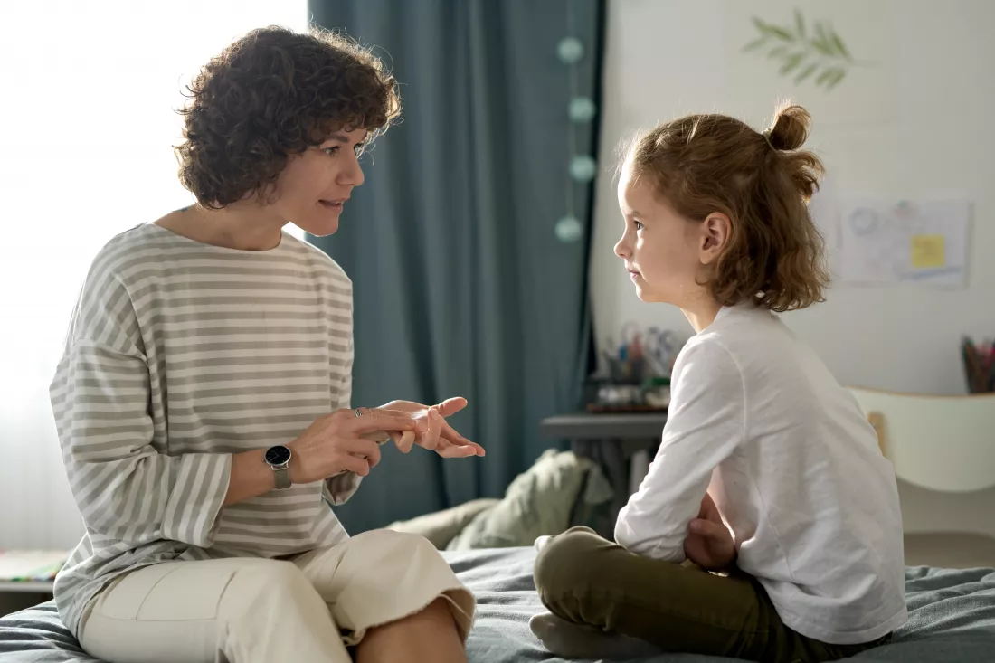 strict-young-mom-talking-her-child-serious-manner-while-they-sitting-bedroom